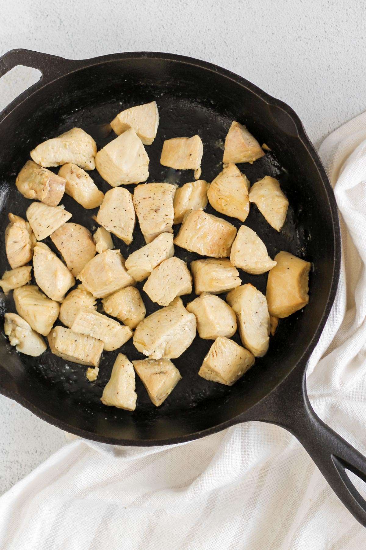Cooked diced chicken in a cast iron skillet.