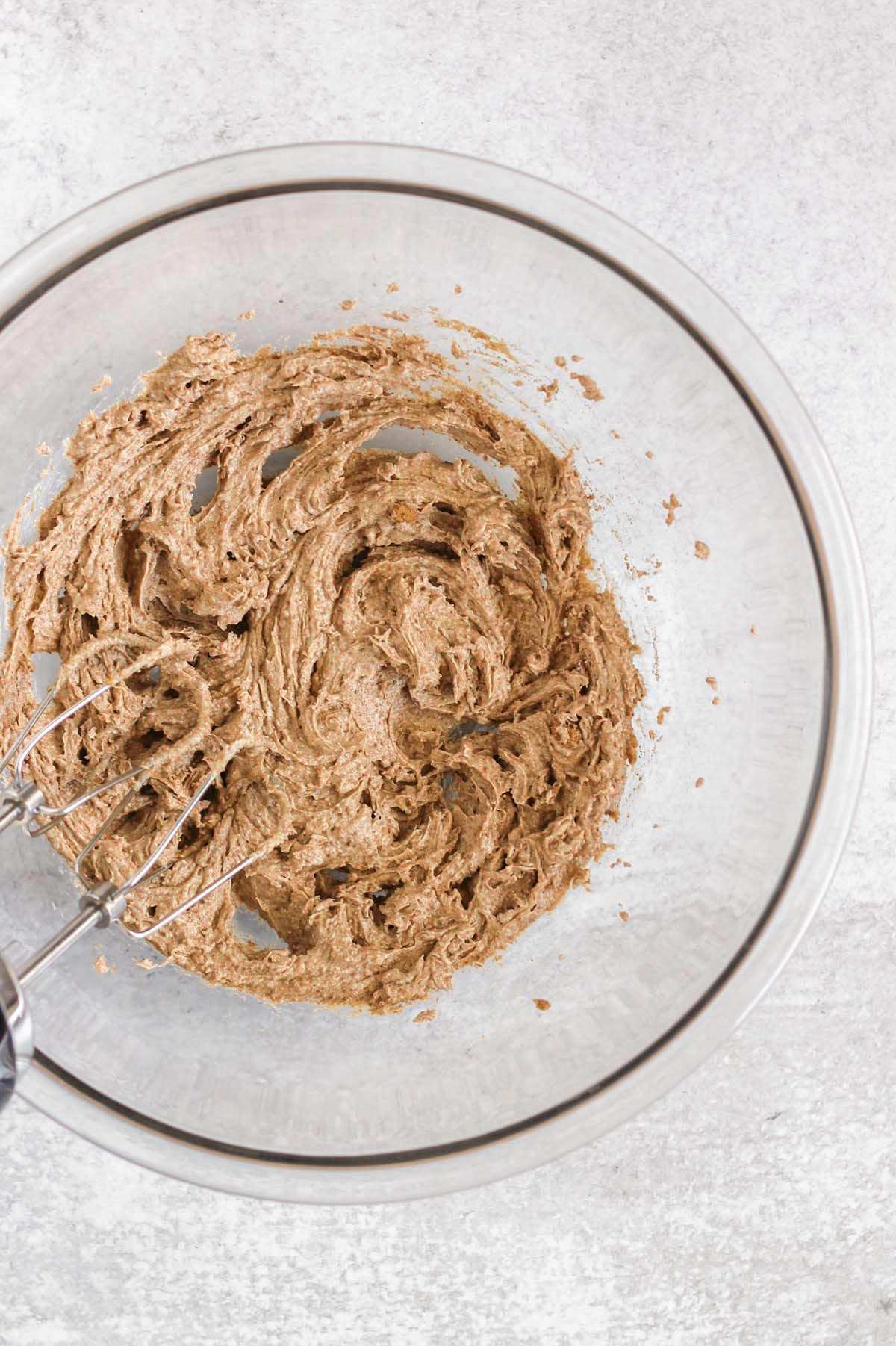 Butter and coconut sugar creamed together in a glass mixing bowl.