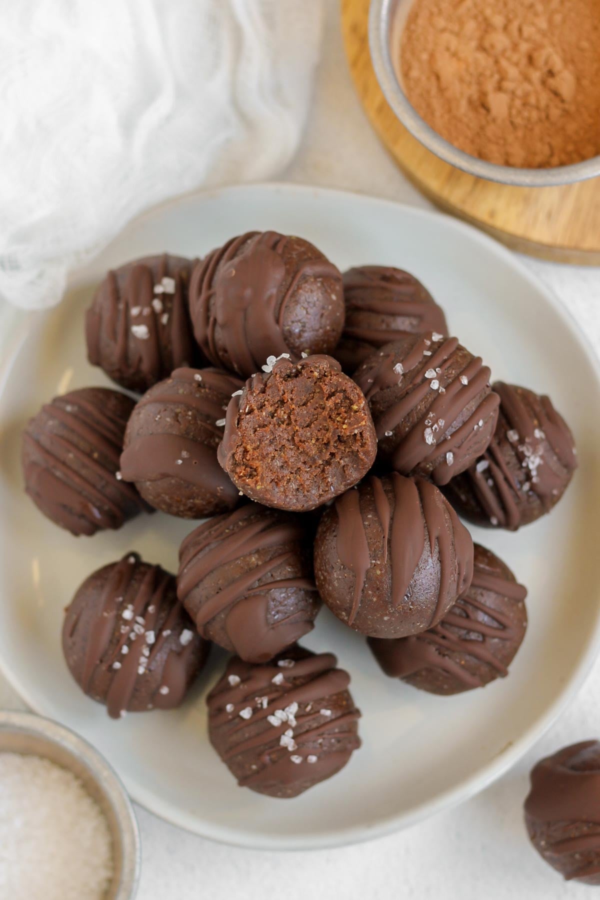 Chocolate brownie bites stacked on a small plate with a bit taken from the top ball.