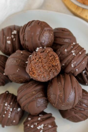 Chocolate brownie bites stacked on a small plate with a bit taken from the top ball.