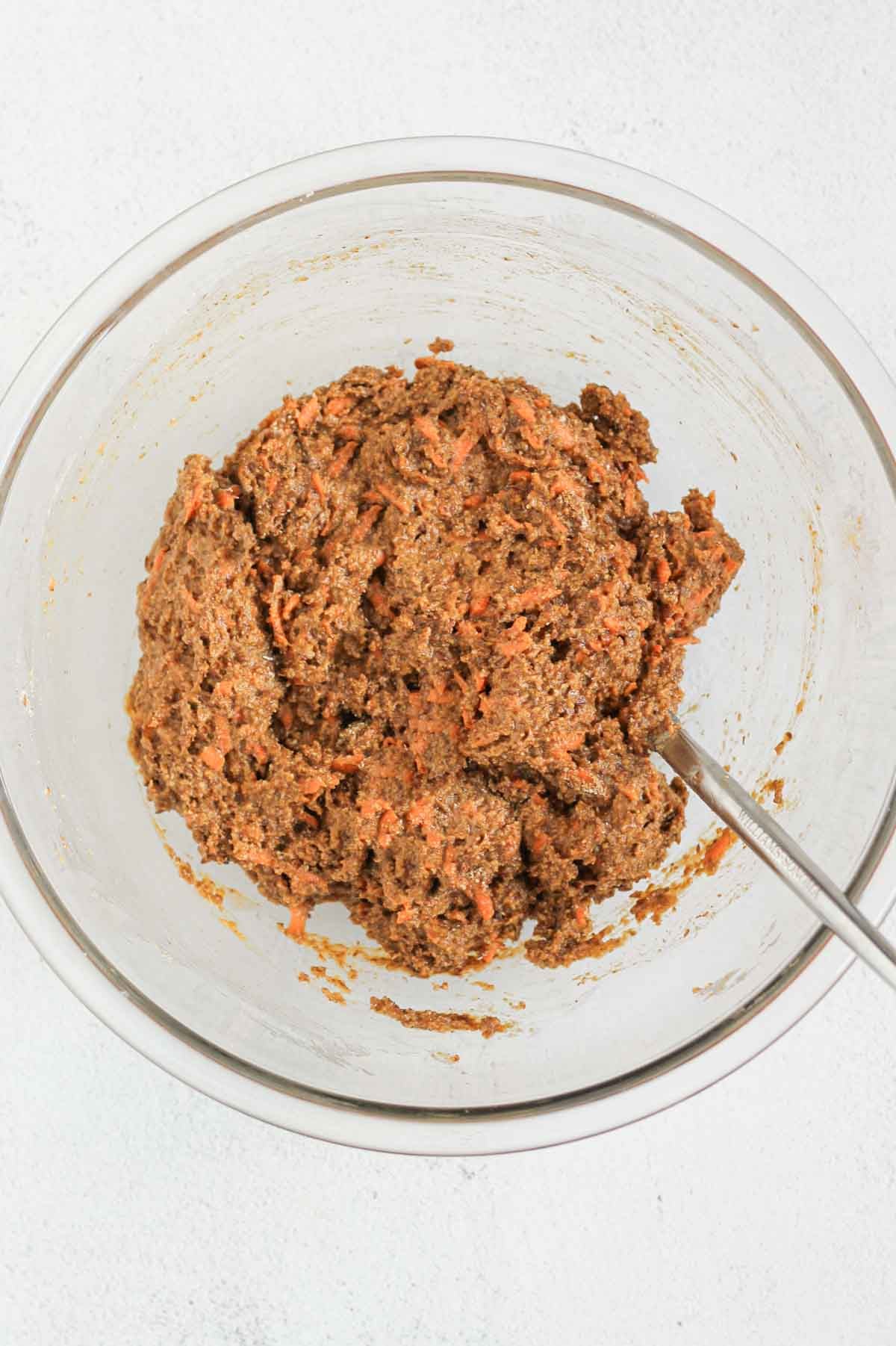 Fully mixed batter for carrot flaxseed muffins in a glass mixing bowl.