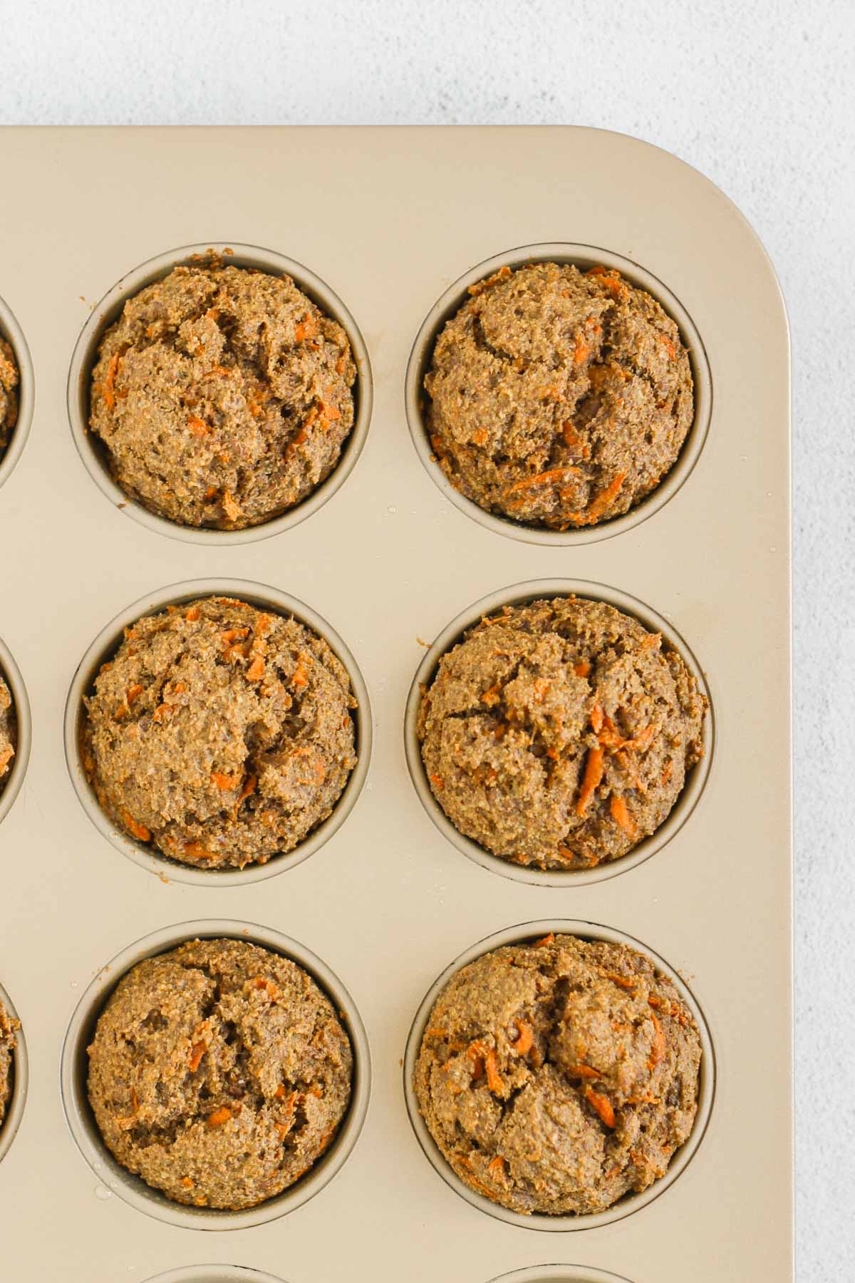 Baked carrot flaxseed muffins in a muffin tin.