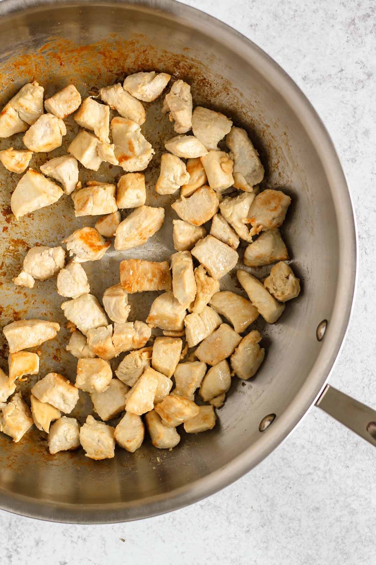 Cooked chicken pieces in a large cast iron skillet.
