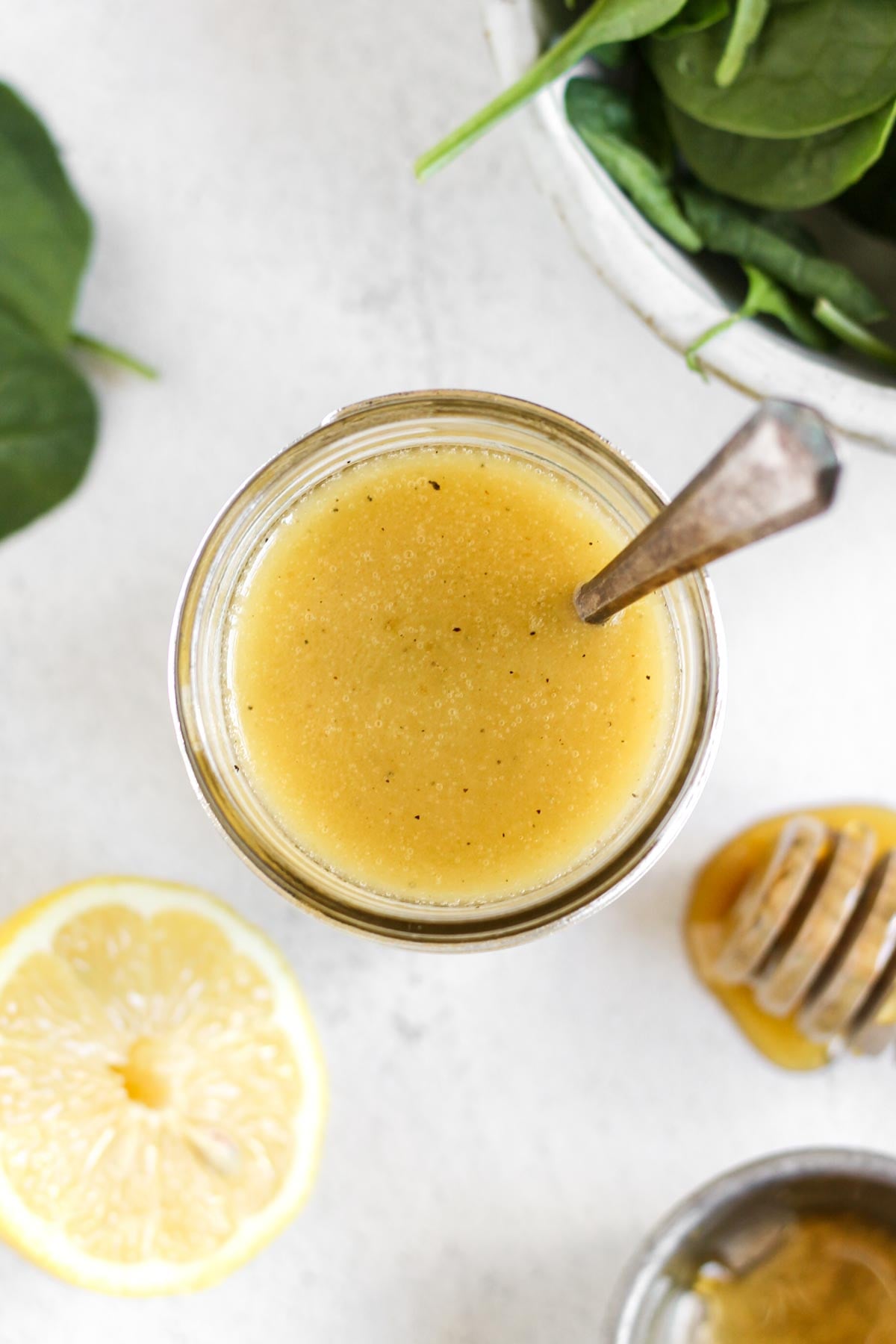 Mason jar filled with lemon honey dressing with a spoon in the jar.