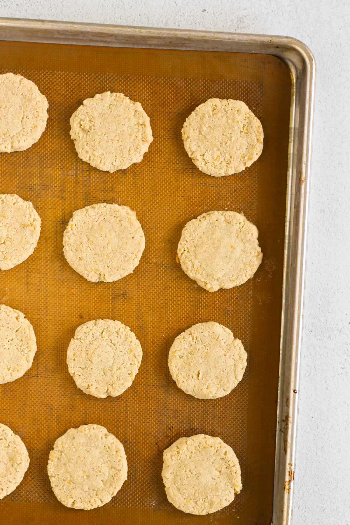 Baked almond flour cookies on a silicone mat lined baking sheet.