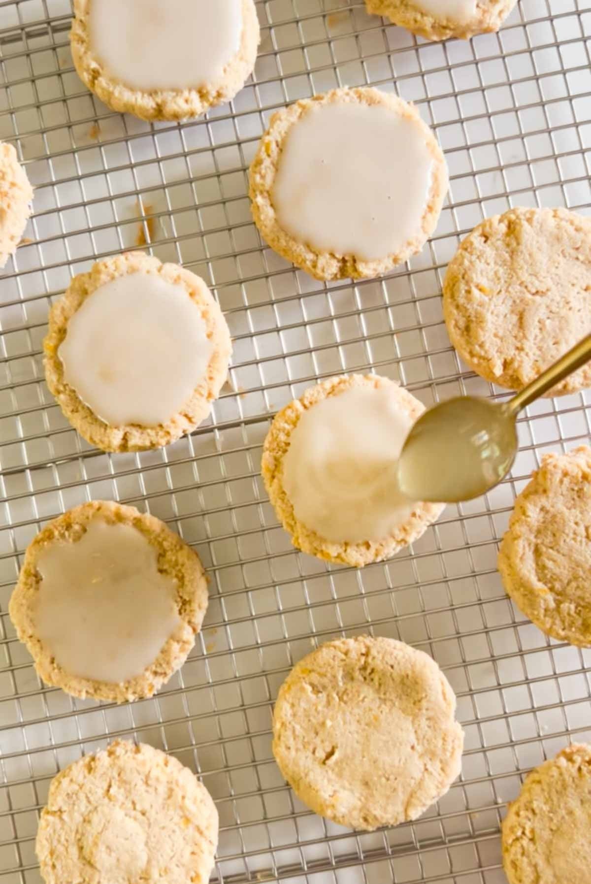Spoon spreading glaze on top of an almond flour cookie.
