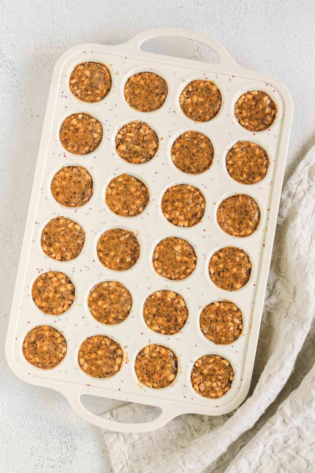 24-cup silicone muffin pan filled with peanut butter brown rice crisp mix.