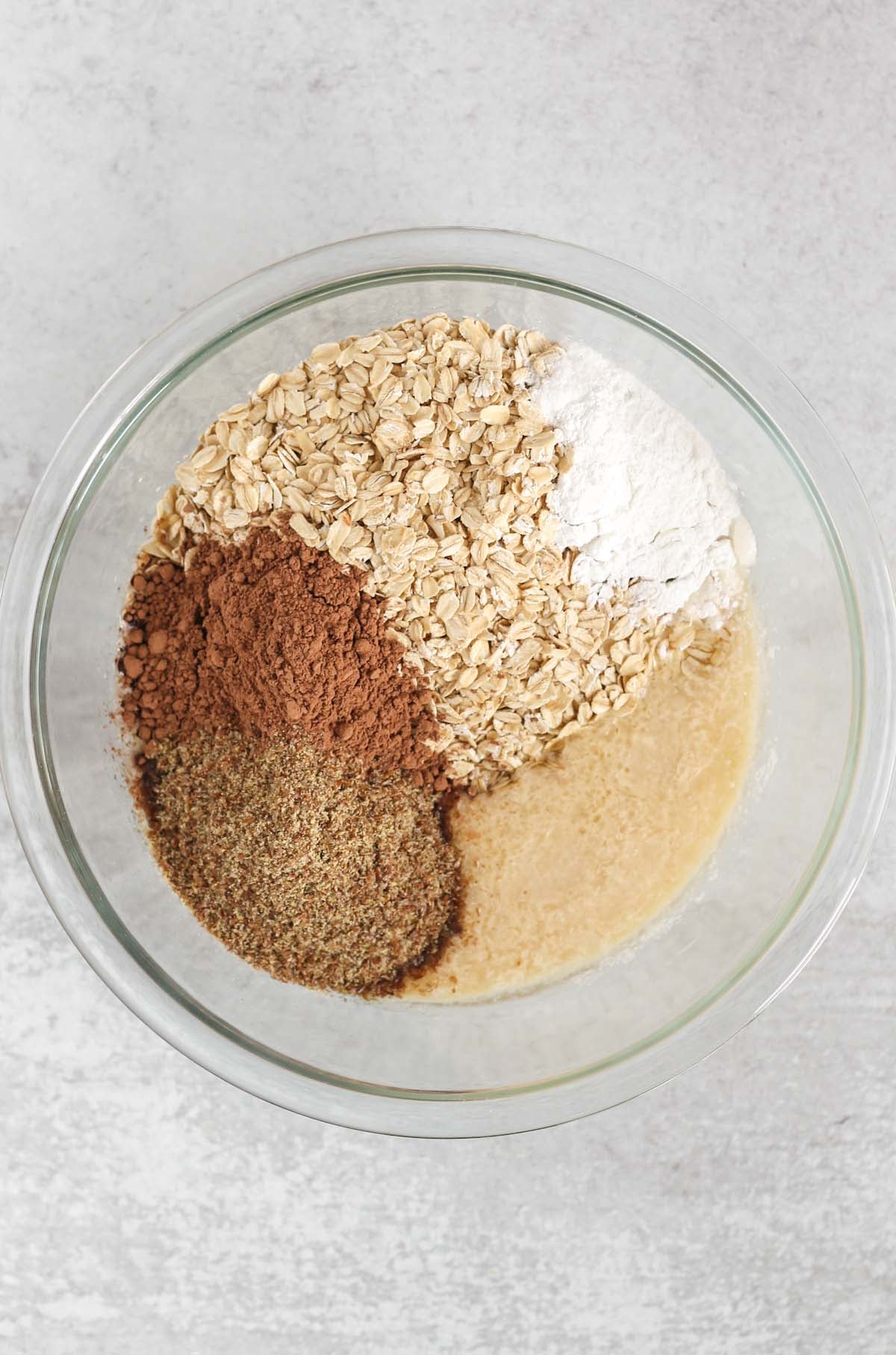 Chocolate baked oats ingredients all added to a glass mixing bowl.