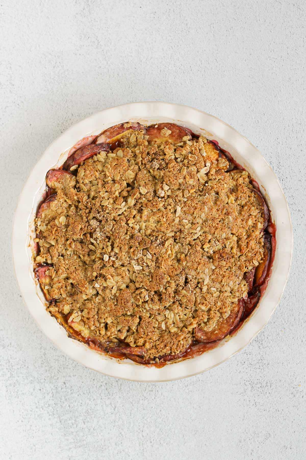 Baked peach crisp in a ceramic pie dish.
