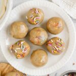 Six birthday cake protein balls on a small round plate.