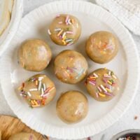 Six birthday cake protein balls on a small round plate.