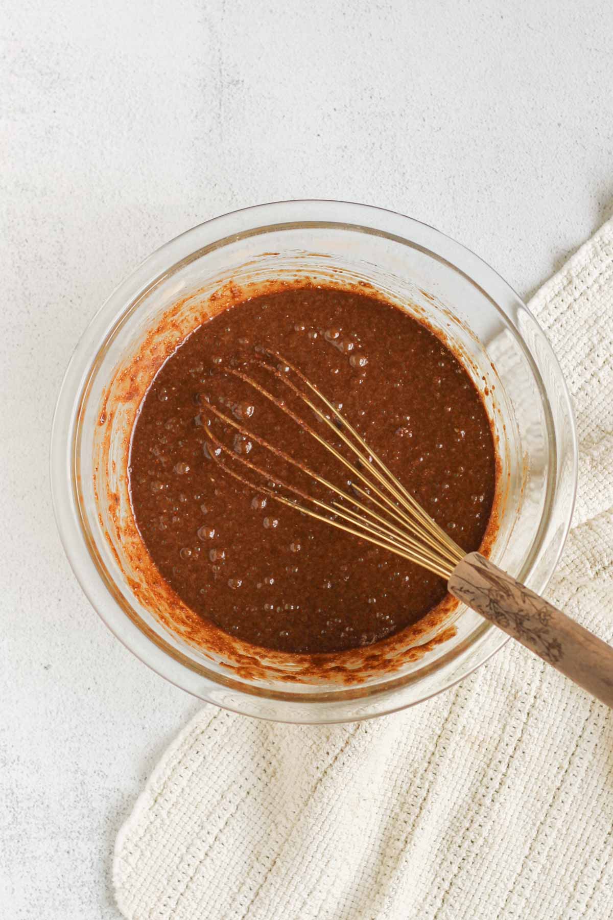 Chocolate flaxseed muffin batter whisked together in a large glass mixing bowl.