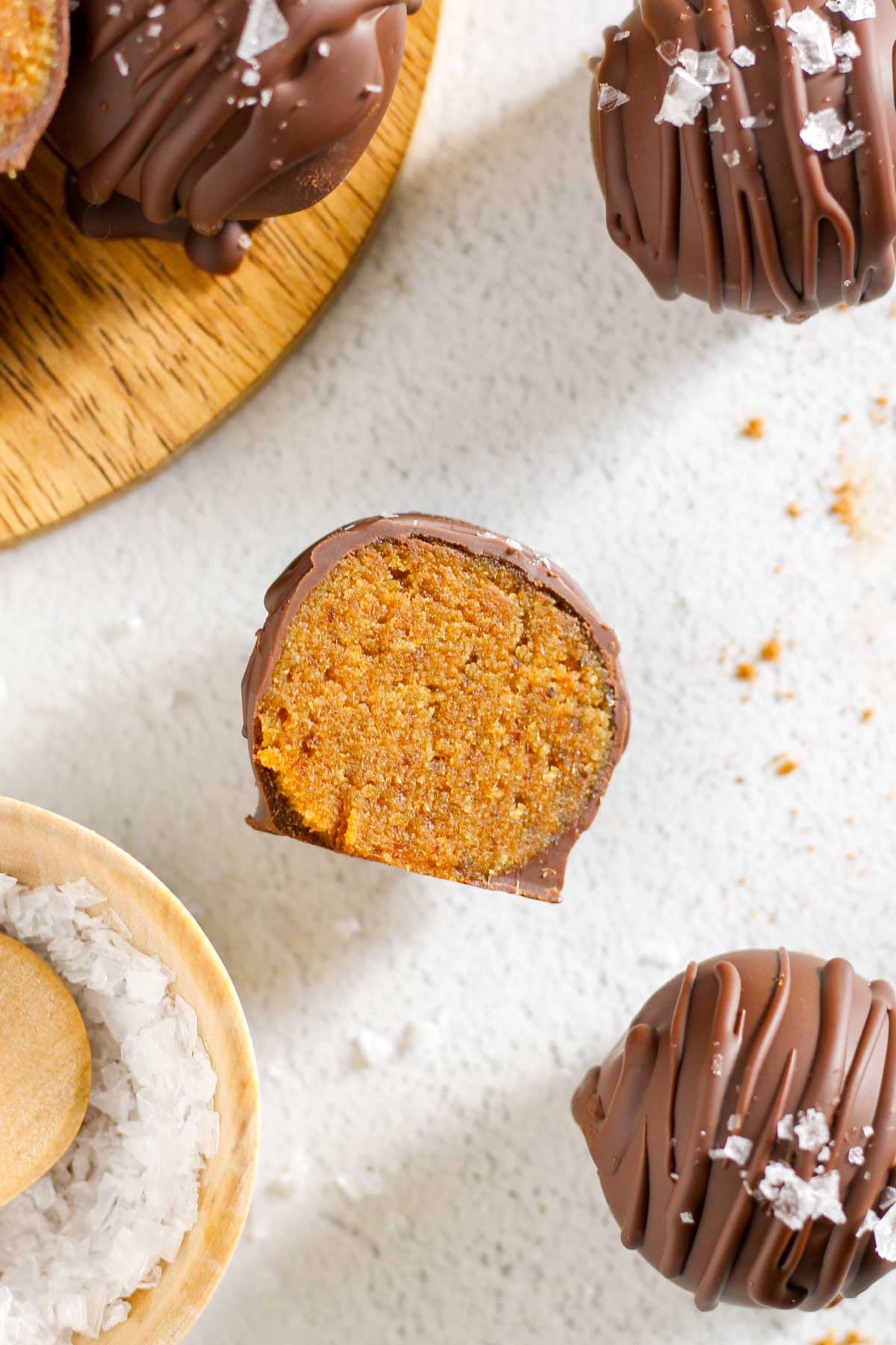 Sliced pumpkin truffle laying on the side with additional truffles set around the half truffle.