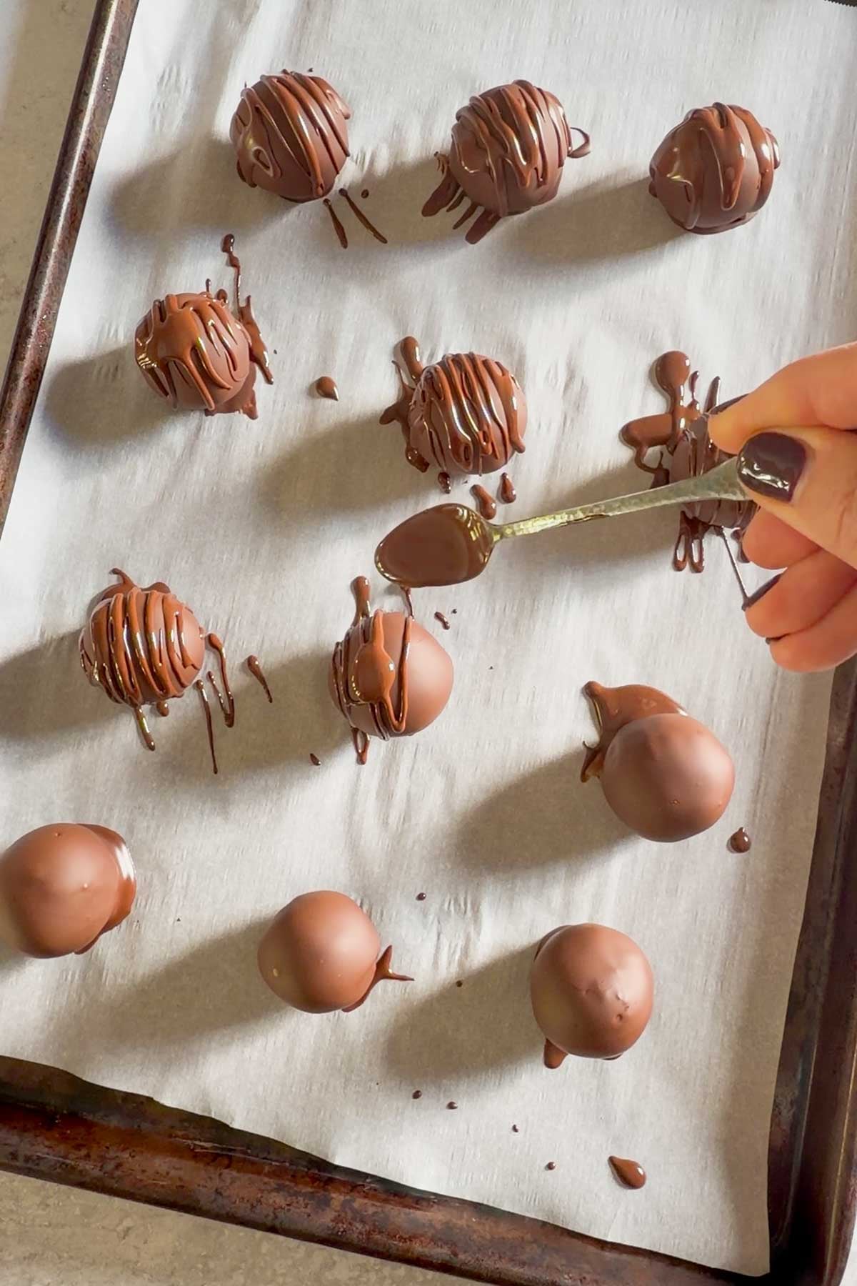 Melted chocolate being drizzled over truffles.