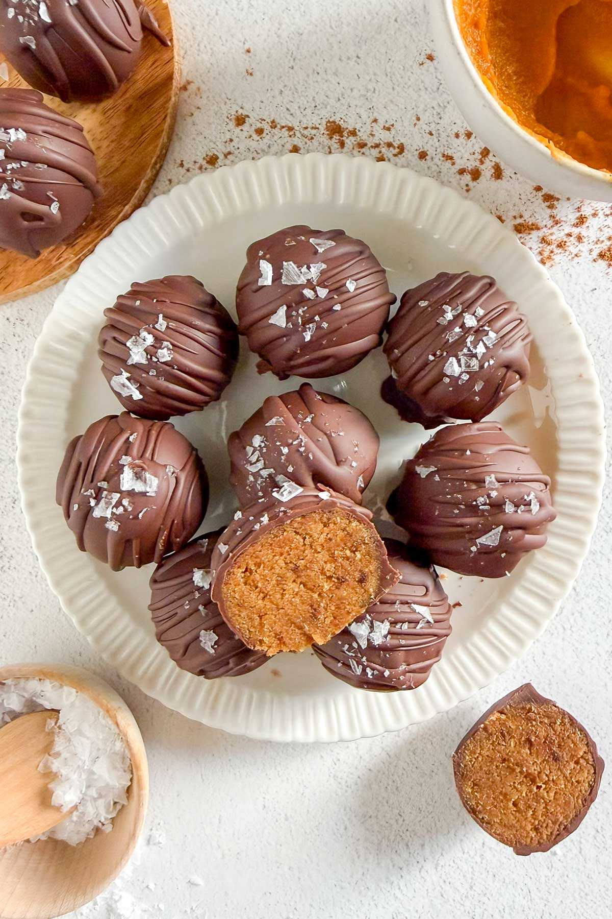 Pumpkin truffles on a small round plate with one truffle cut in half. Half truffle lying on the plate and other half next to the plate.