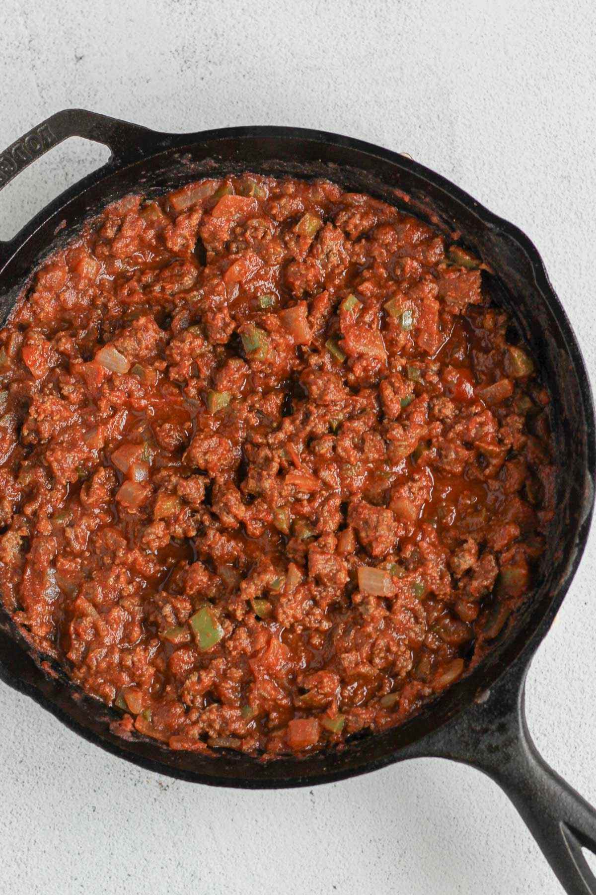 Ground beef with sloppy Joe sauce cooked in a cast iron skillet.