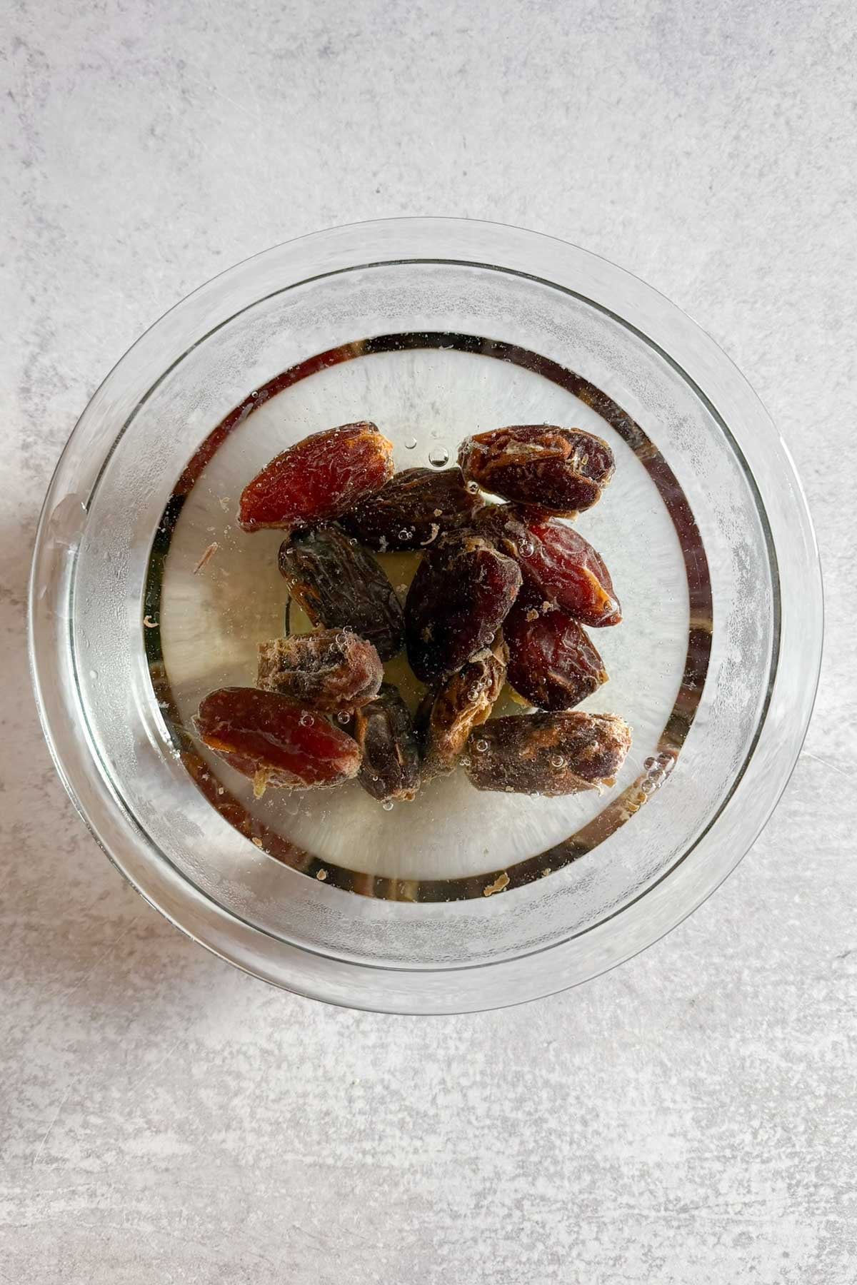 Dates soaking in water in a glass bowl.