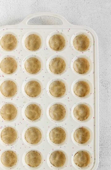 Silicone mini muffin pan with almond flour dough added to each muffin cavity.