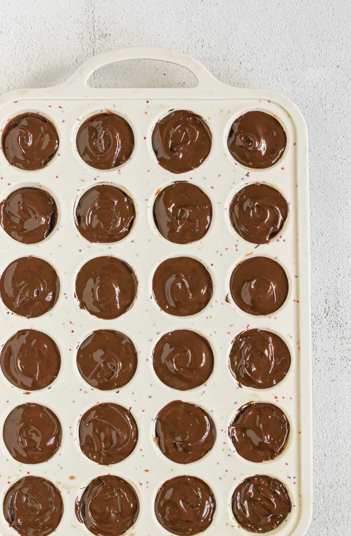 Melted chocolate added to the top of each Twix bite in a silicone mini muffin pan.