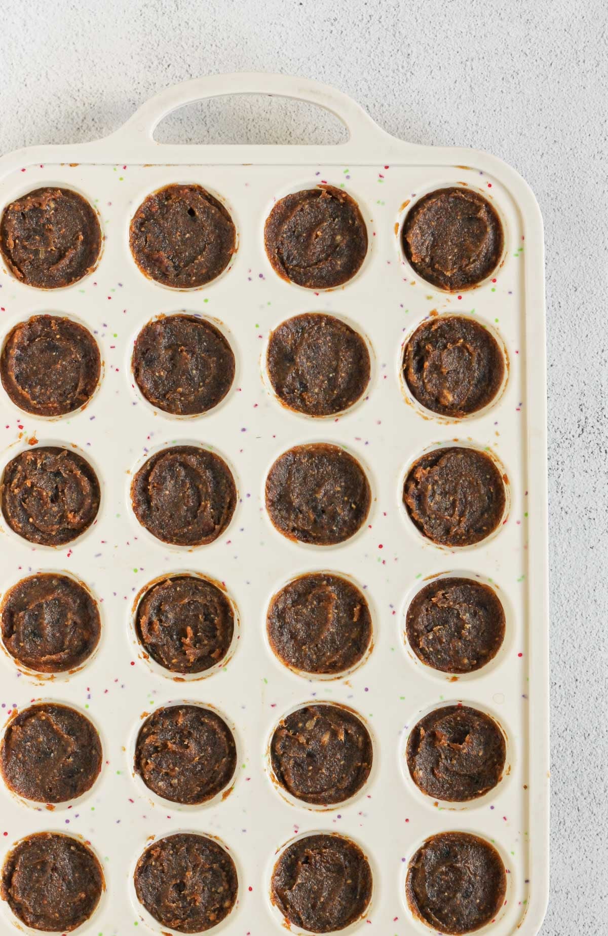 Silicone mini muffin pan with date caramel layer added to shortbread base.