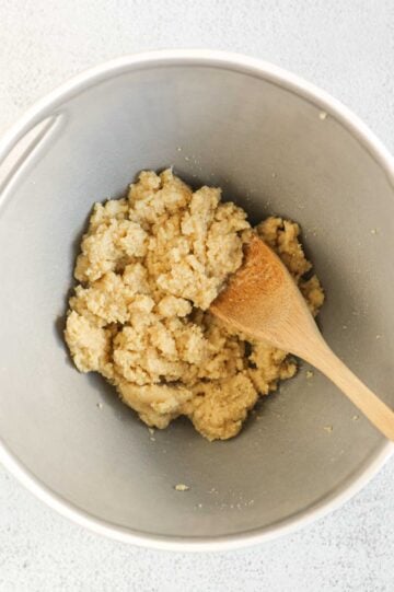 Almond flour shortbread ingredients mixed together in a mixing bowl with a wooden spoon.