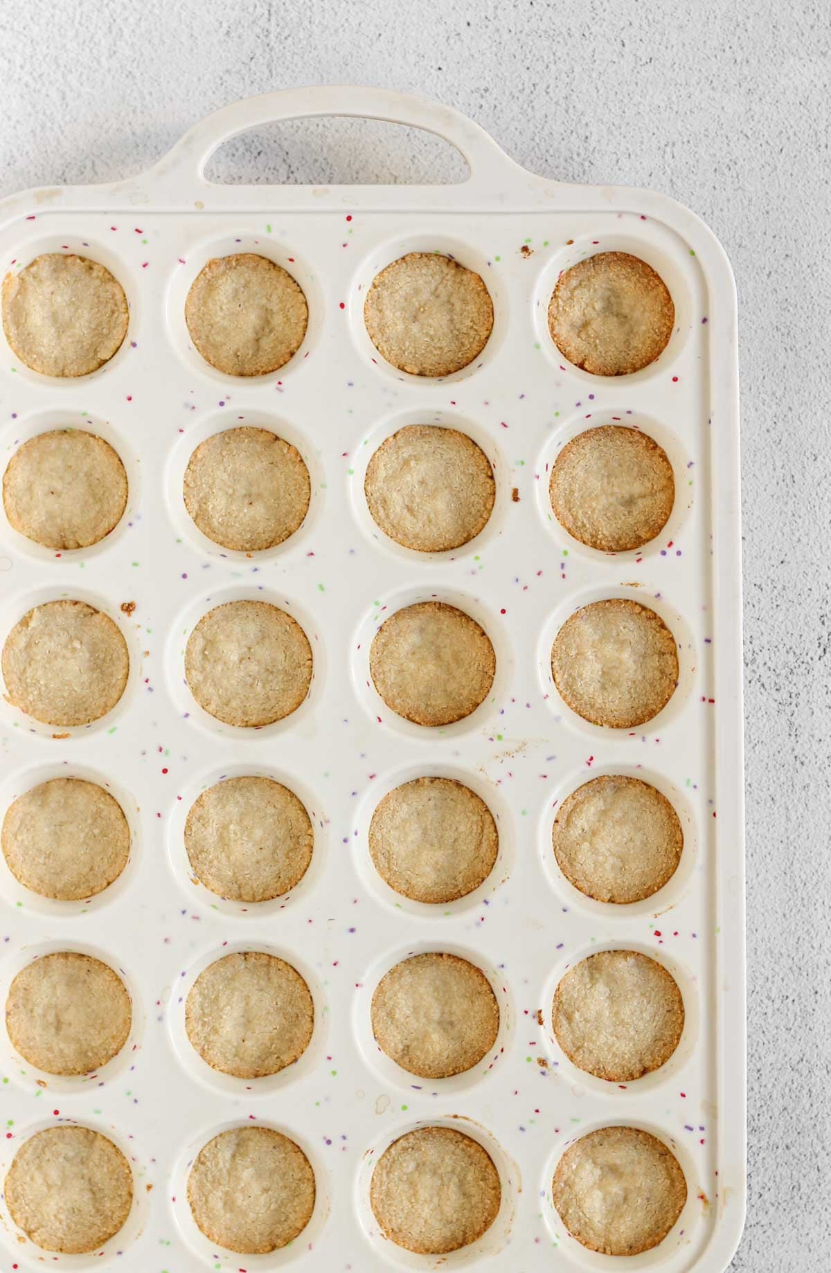 Baked almond flour shortbread crust in a silicone 24-cup muffin pan.
