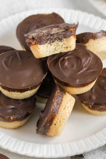 Small round Twix bites stacked on a small plate with a bite taken from the top Twix bite.